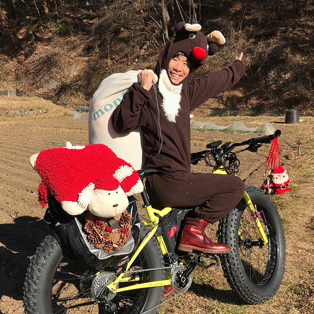 Right side view of a cyclist wearing a reindeer costume, seated on yellow Surly fat bike and smiling