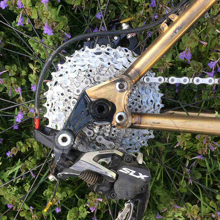 Close up view of the rear drop outs, cassette and derailleur of a Surly Krampus bike, gold