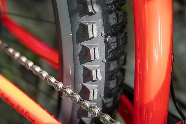 赤とオレンジの Surly の自転車に装着した Surly Dirt Wizard リアタイヤのラグとサイピングのアップ