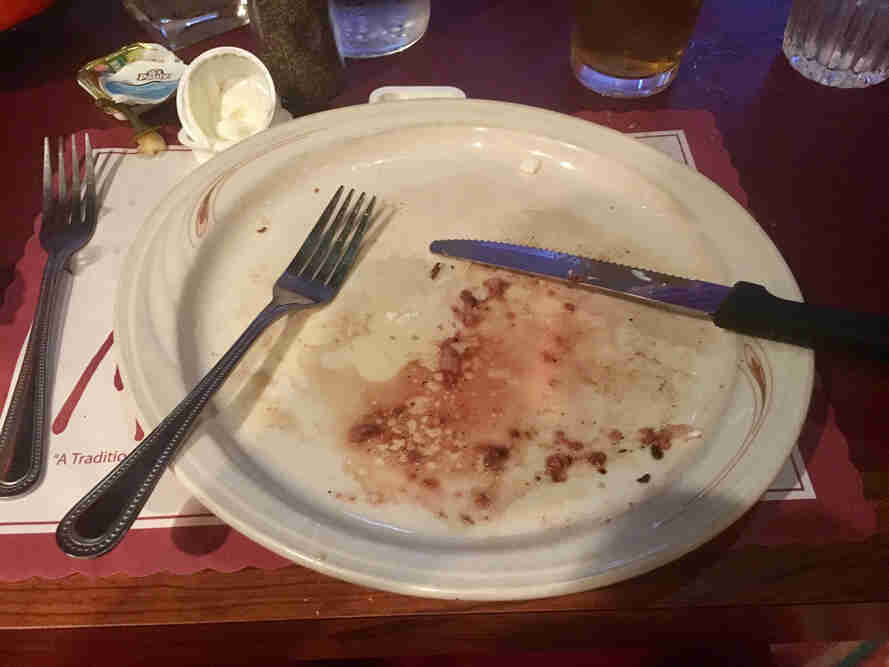 An empty plate with a knife and fork on top