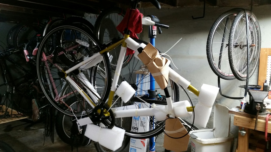Right side view of a partially assembled bike on a stand, in a room with bikes and parts in the background