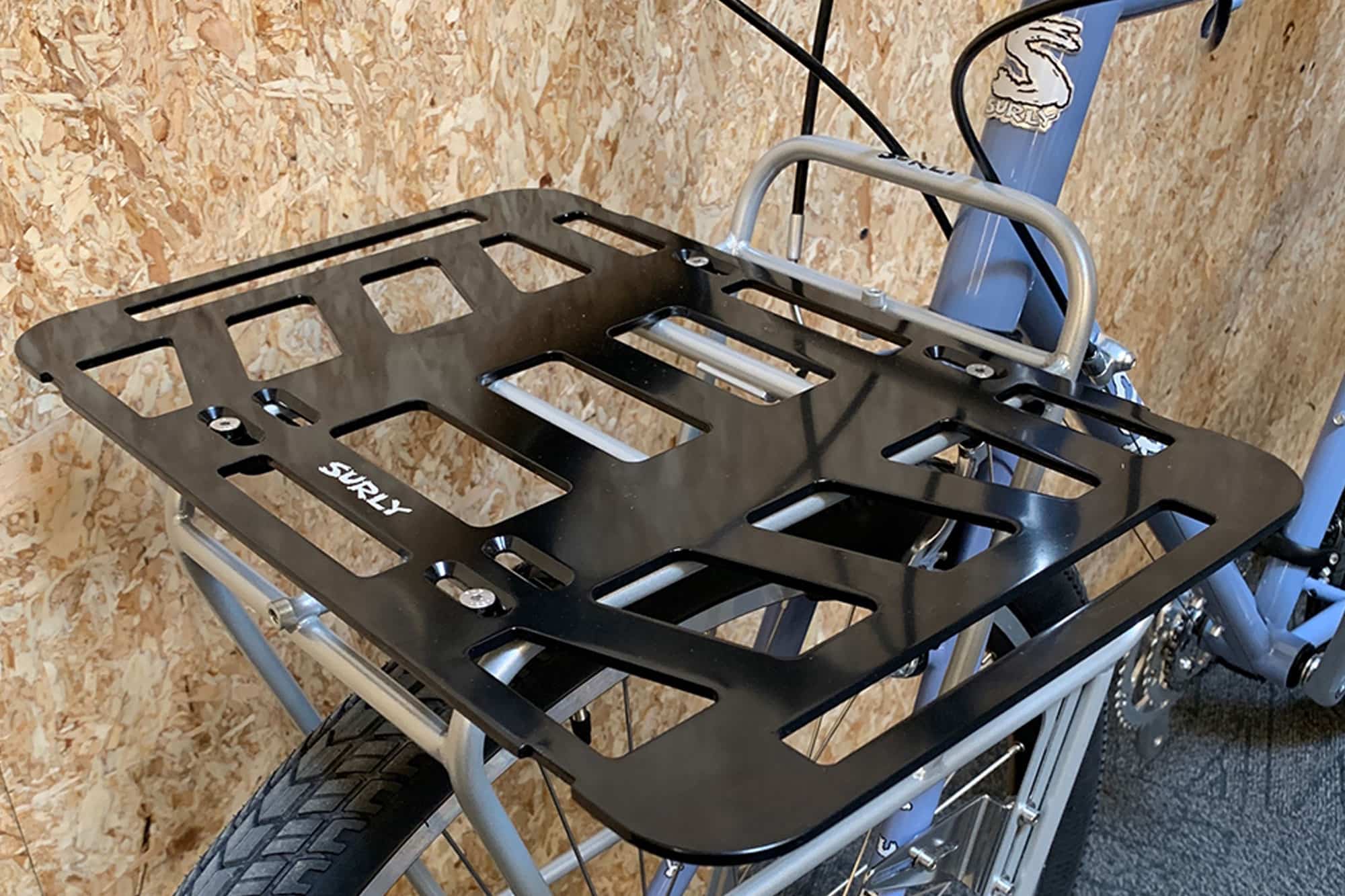 Surly TV Tray front rack, black, mounted to a Surly bike in front of an OSB wood wall
