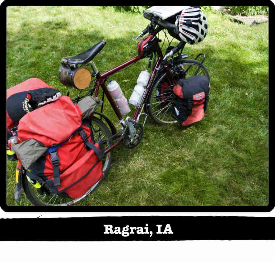 Right side view of a dark red Surly Long Haul Trucker bike, loaded with gear, on grass -Ragbrai, IA tag below image