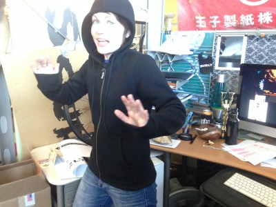 Front view of a person wear a black Surly Hoodie for woman, standing in front of a desk in an office