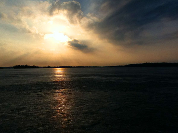 A frozen lake at sunset with clouds in the sky
