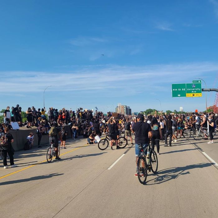 A group of pedestrians and cyclists gather on the I-35 freeway bridge in Minneapolis