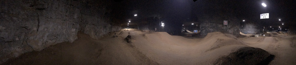 A dirt bike race track inside of a large cavern with lights above