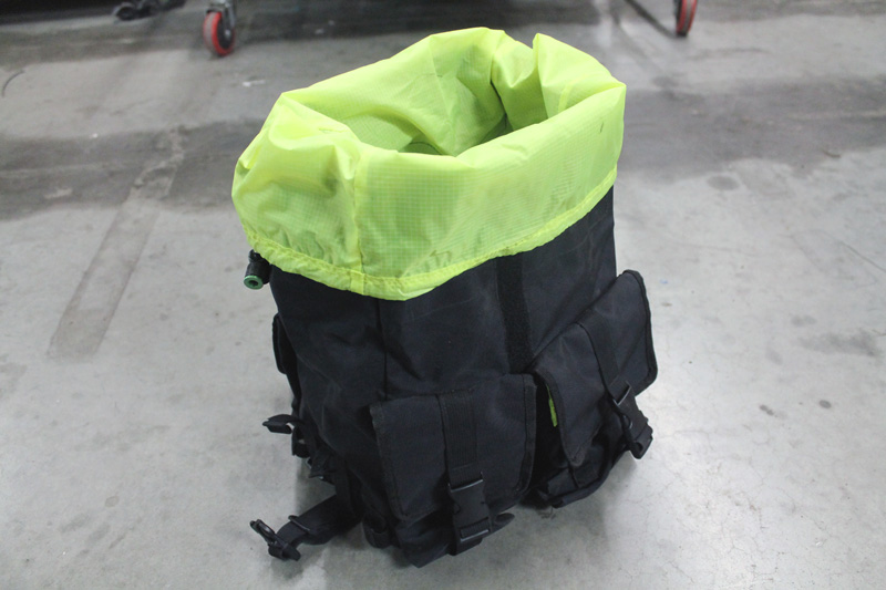 A Surly Petite Porteur House bag, black outside and lime green inside, set on a concrete floor