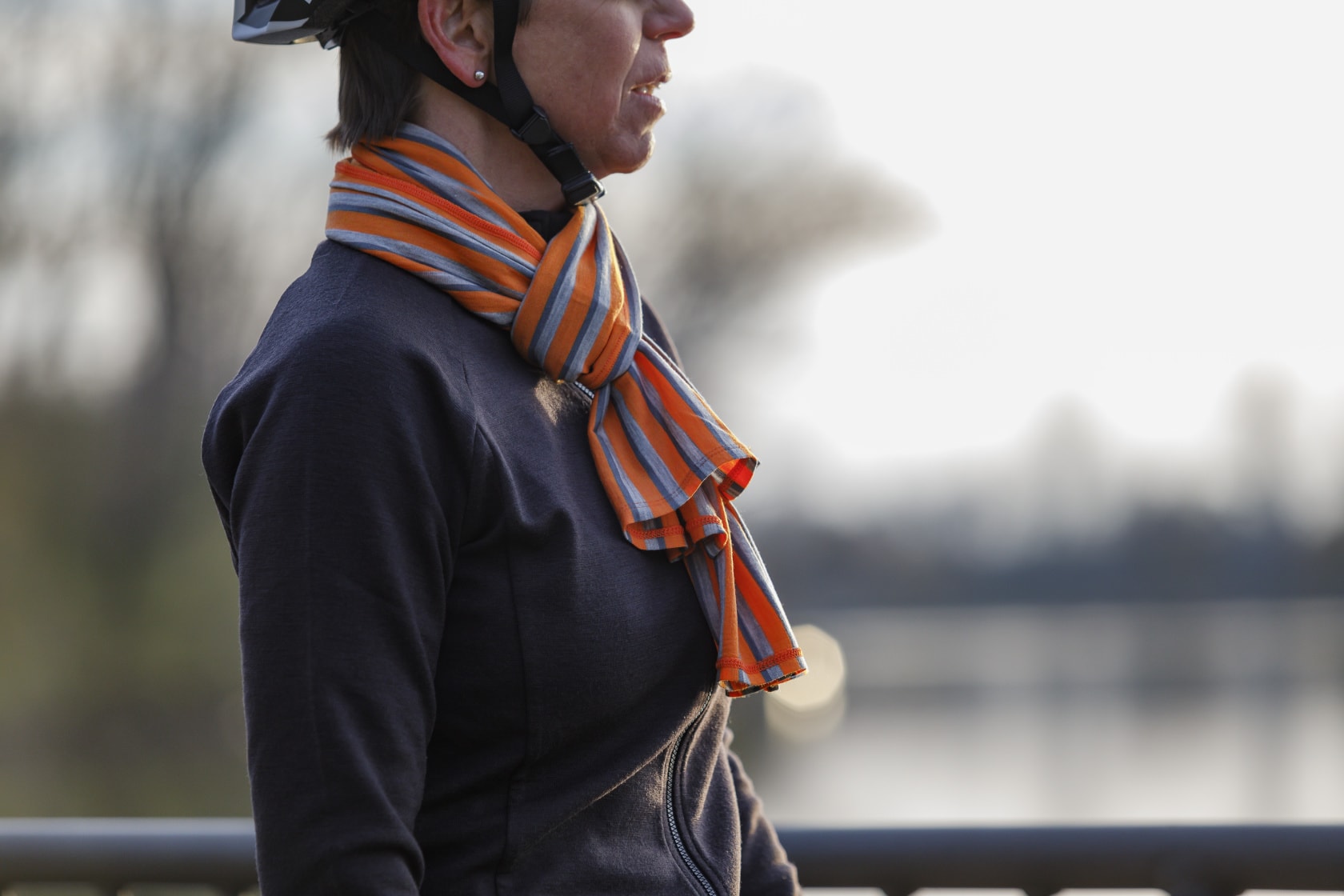 Right profile view of a person wearing a Surly Wool Scarf - Orange, Light Gray and blue parallel stripes 