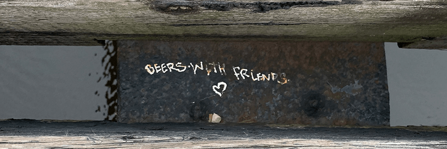 Metal plate with the words 'beer with friends' and heart written in white between to railroad ties