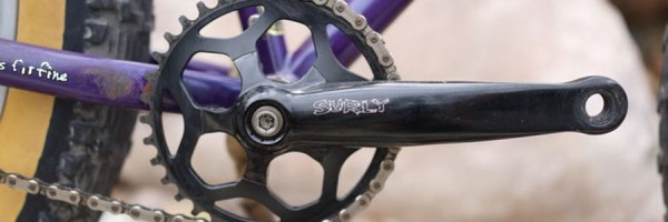 紫色の Surly Pugsley ファットバイクに装着されたチェーンとリアタイヤの一部と黒い Surly のクランクセットのアップ