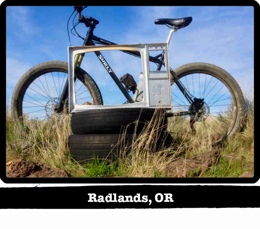 Left side view of a Surly Karate Monkey bike, black, in front of a TV frame on tires - Radlands, OR tag below image