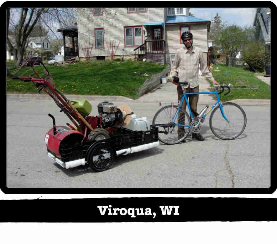Cyclist standing on a street with a Surly bike, trailer with a soil tiller inside - Viroqua, WI tag below image