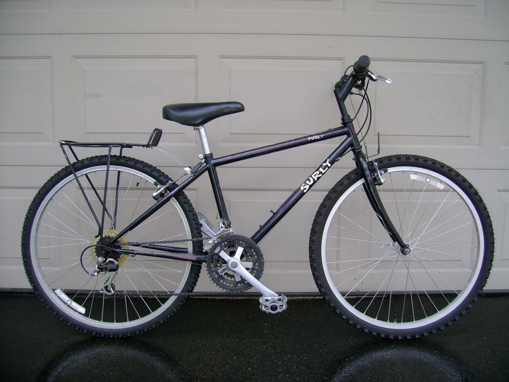 Right side view of a black Surly bike, parked in front of a garage door
