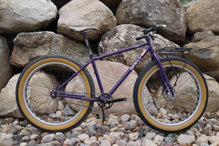 Close up of a black Surly crankset with a portion of the chain and rear tire on a purple Surly Pugsley fat bike