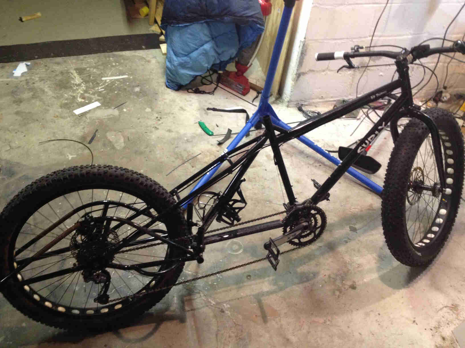 Right side view of a black Surly Big Dummy bike with a front fat wheel, without a seat or post, on a concrete floor