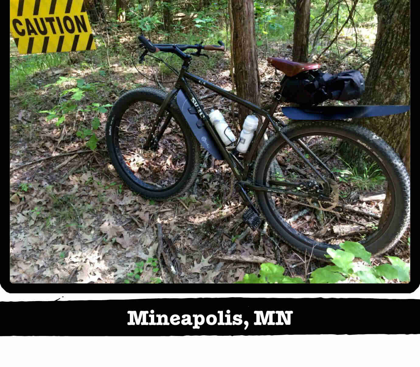 Left side view of a Surly ECR bike, olive, in the woods with a caution sign - Minneapolis, MN tag below image