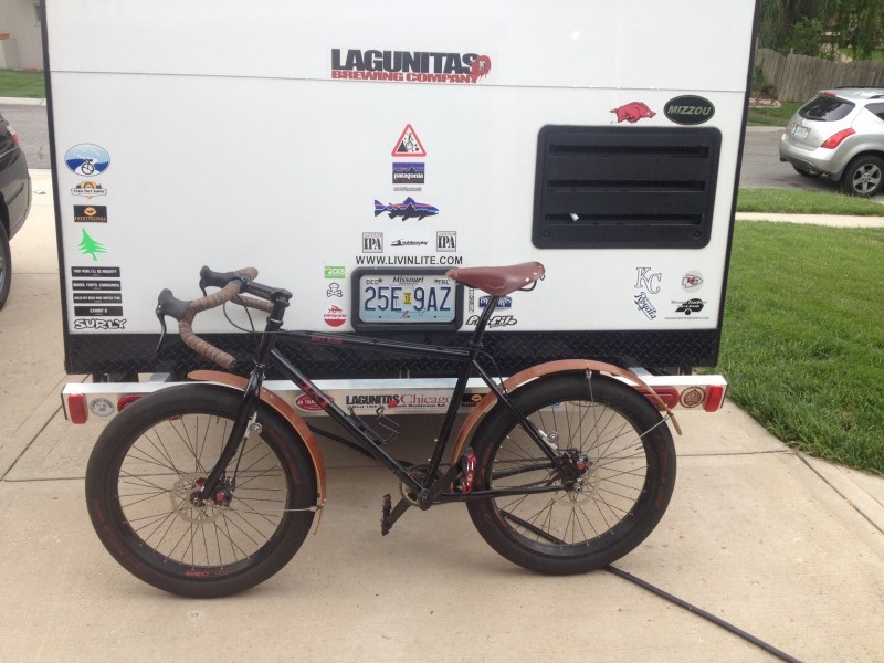 Left side view of a black Surly 1x1 bike with fenders, leaning against a camper tailgate, on a driveway