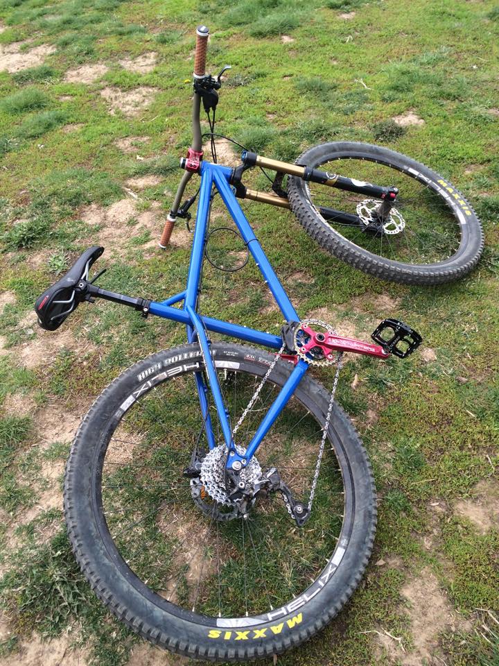 Downward, vertical right side view of a blue Surly Instigator bike, lying on it's side in grass