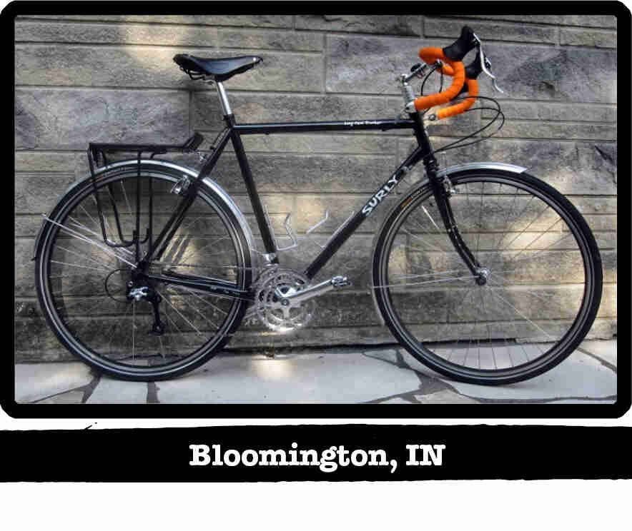 Right side view of a black Surly Long Haul Trucker bike, in front of a stone wall - Bloomington, IN tag below image