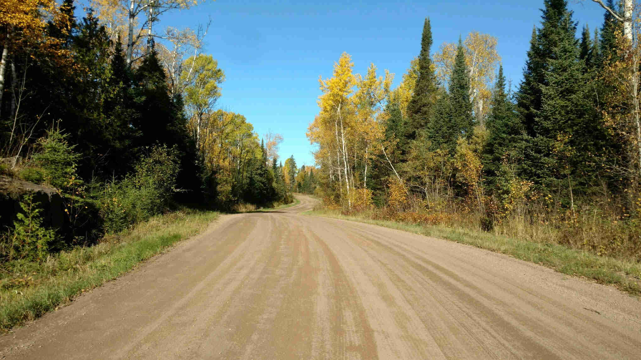 View facing down a wide gravel road with trees on the sides