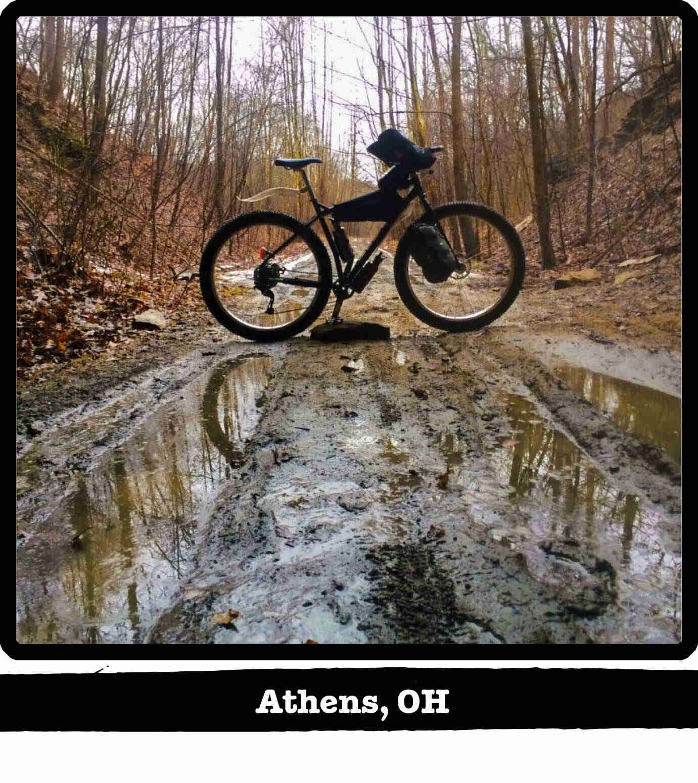 Right profile of a Surly ECR bike standing across a muddy trail in the woods - Athens, OH tag below image