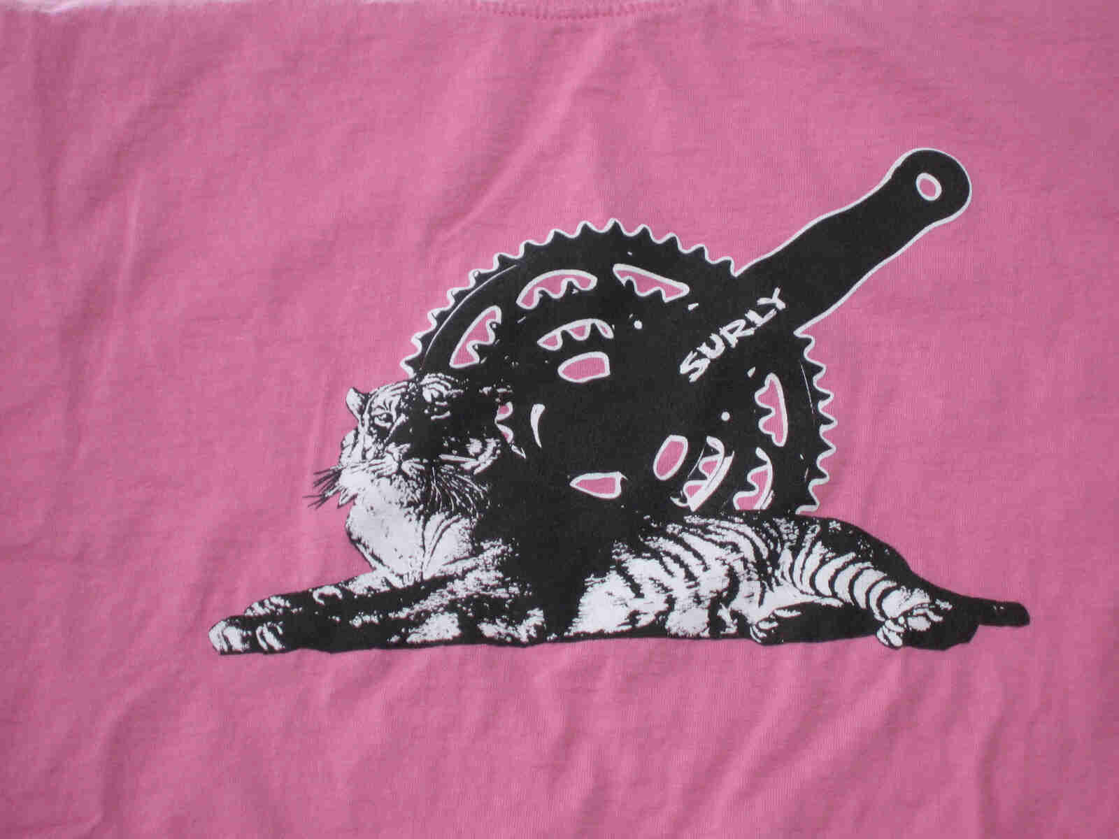 Front, chest area view of a pink Surly Bikes t-shirt with a graphic of a bike crank and a tiger