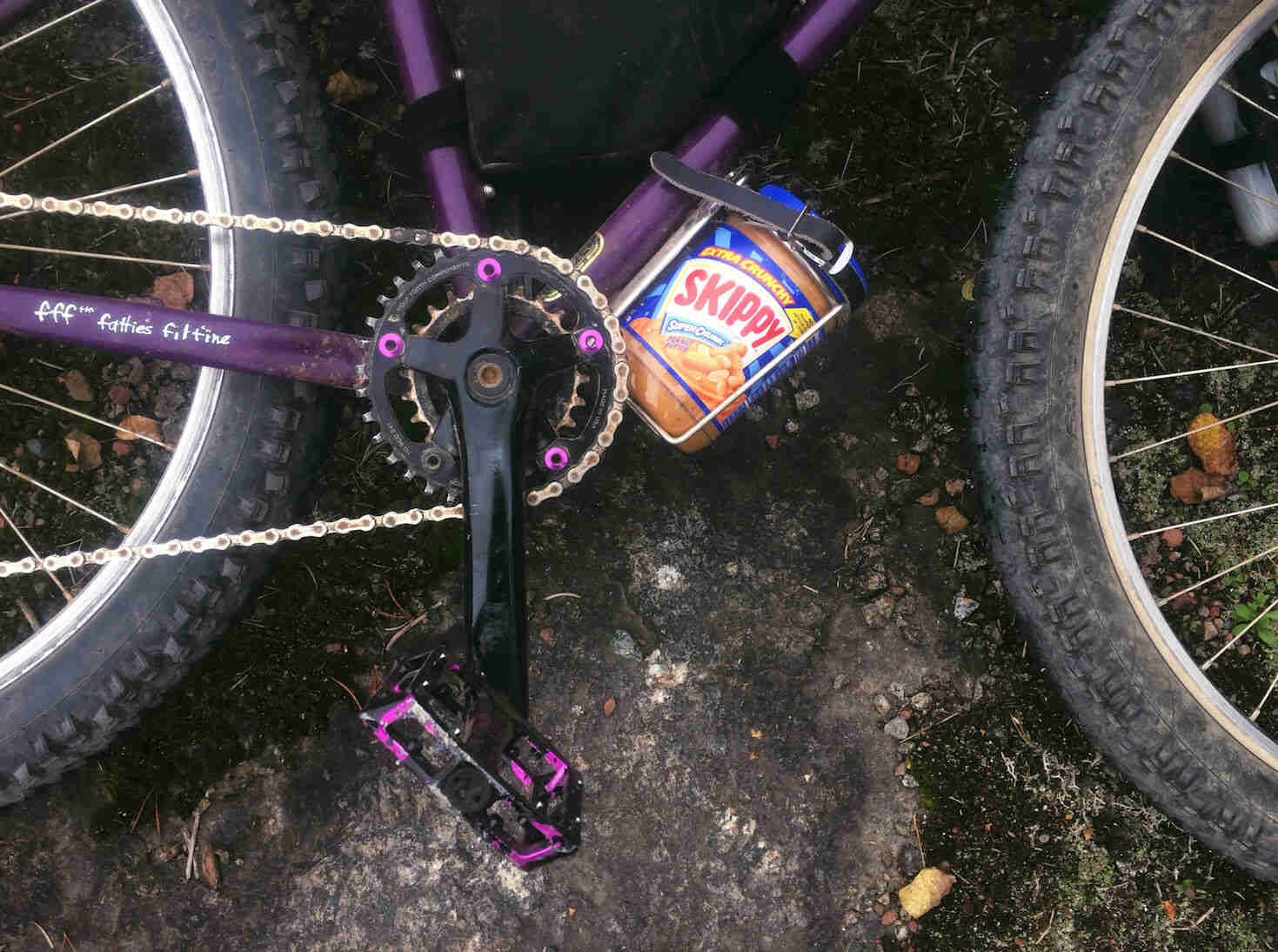 Downward, right side close up view of a Purple Surly bike with a jar of peanut butter in the water bottle cage